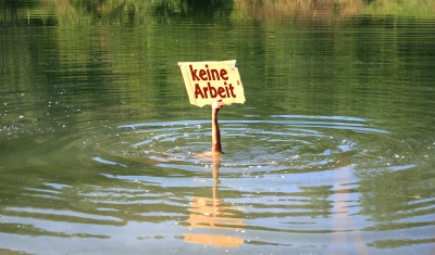 Hand mit beschriftetem Schild ragt aus Wasser